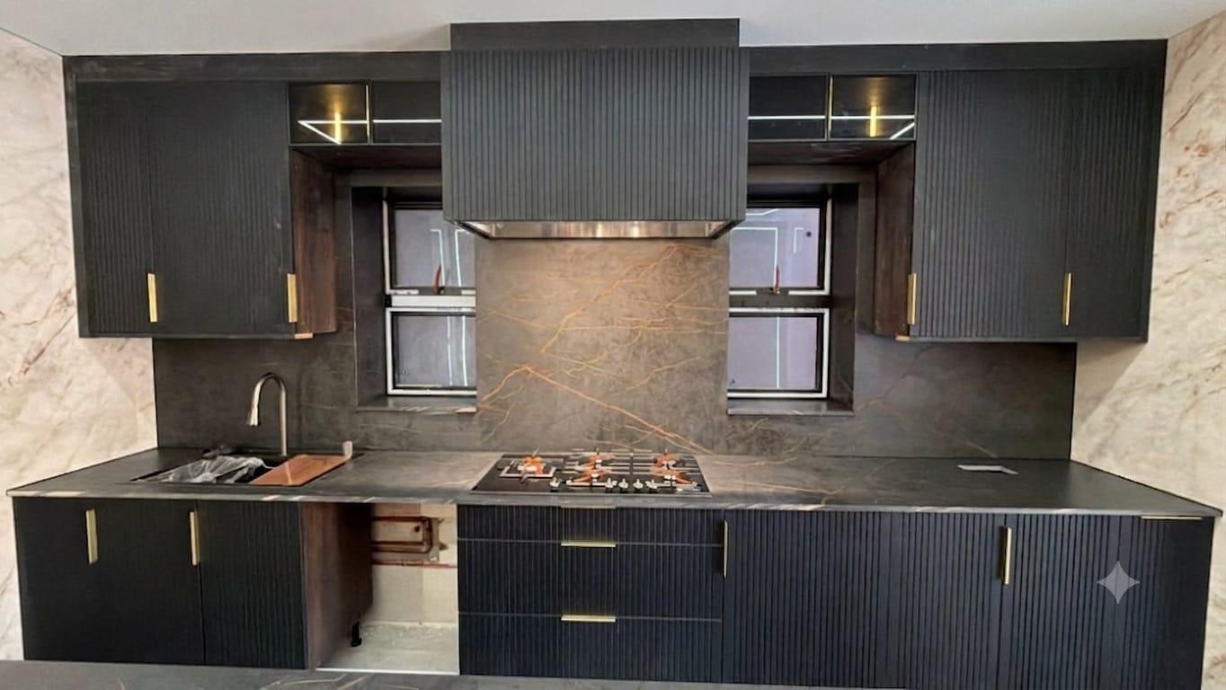 Black fluted kitchen with dark marble worktop and copper-veined splashback